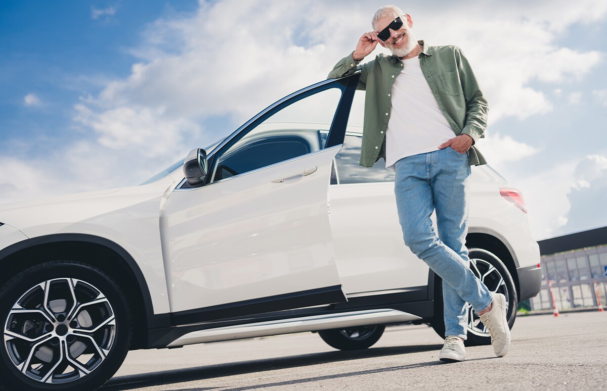 Hombre feliz junto a su coche nuevo