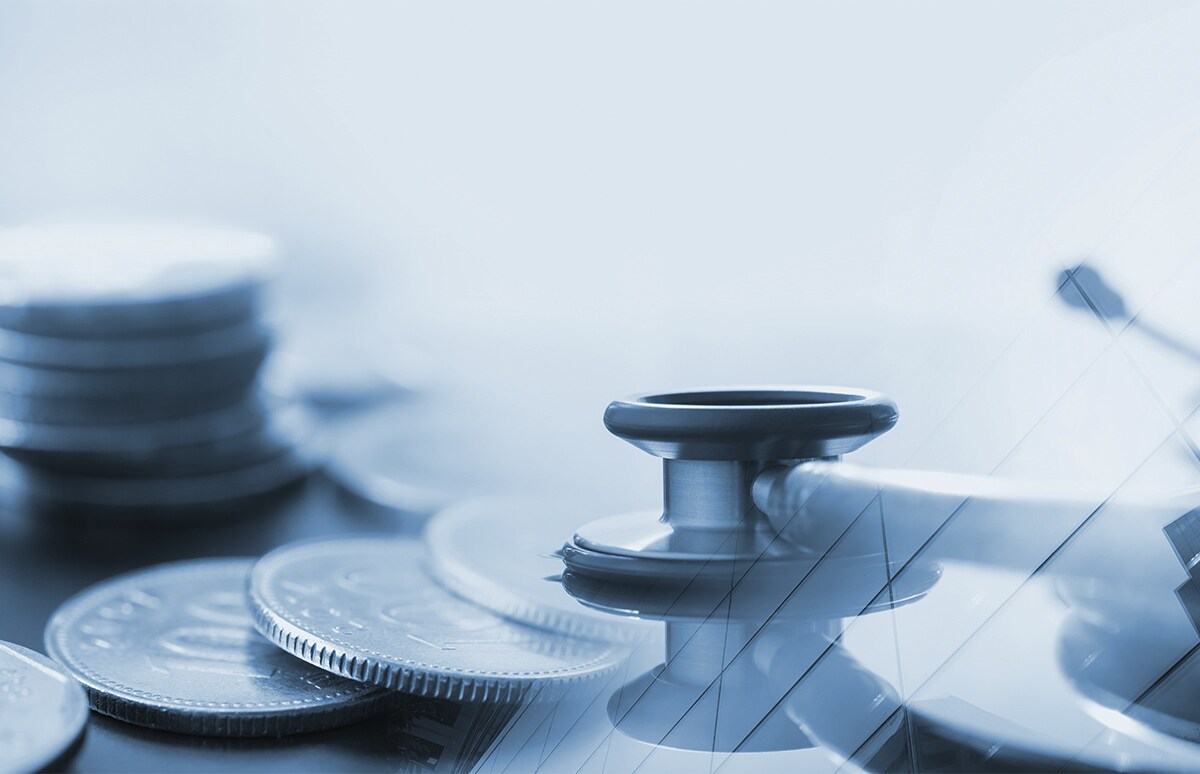 Composición conceptual con un fonendoscopio apoyado sobre monedas y gráficos financieros superpuestos, en tonos fríos y ambiente clínico