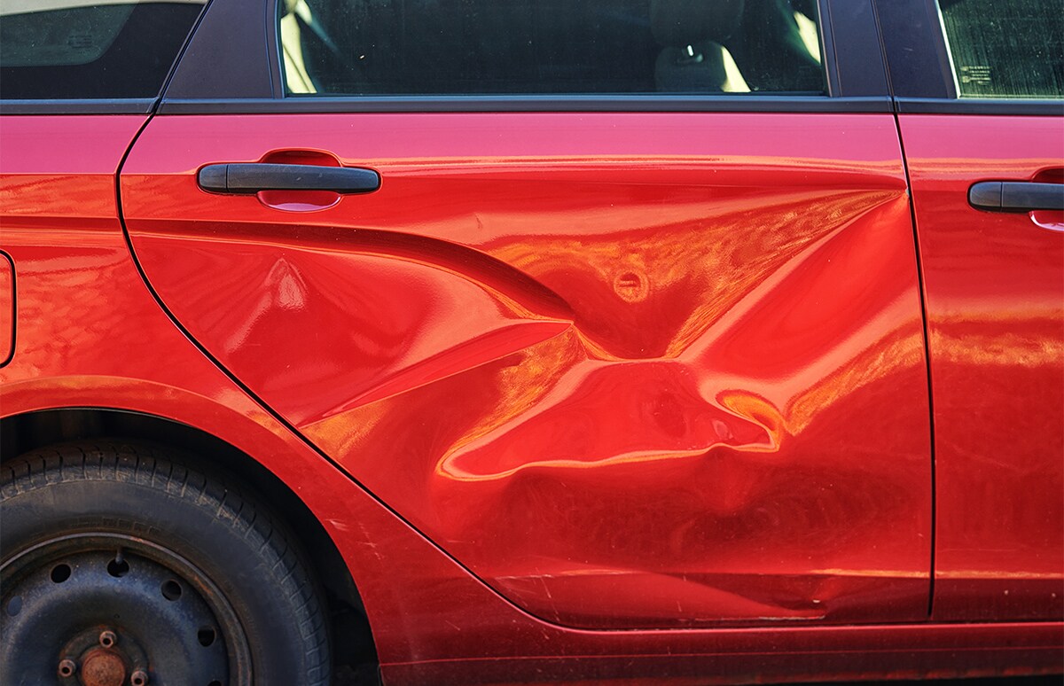 Puerta trasera abollada de un automóvil de color rojo