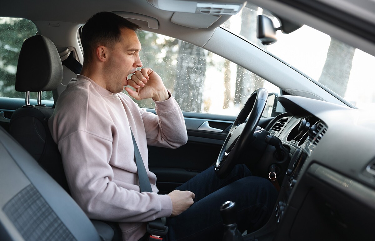 Joven bostezando al volante de su automóvil