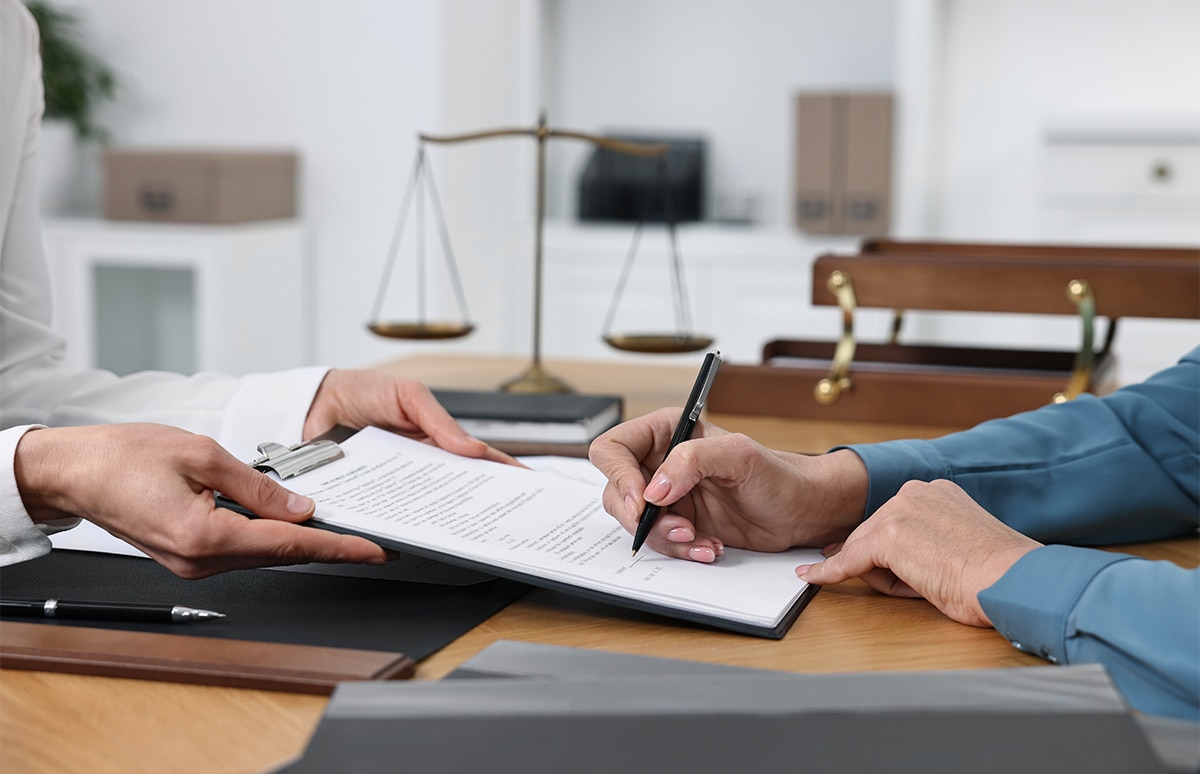 Mujer firmando documentos del seguro de vida en un bufete de abogados
