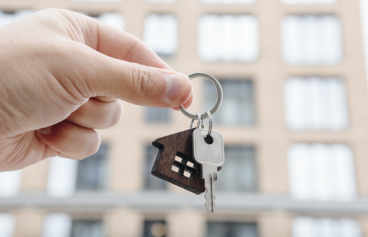 Mano sujetando un llavero con la llave de un piso