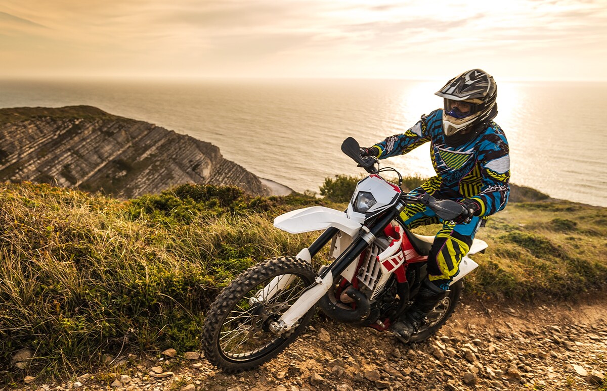 Joven realizando enduro por una montaña junto a la costa
