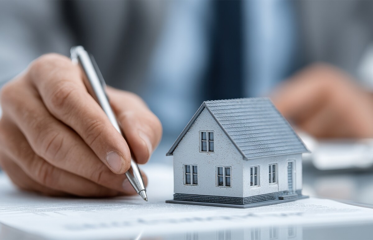 Hombre firmando documentación junto a una maqueta de una vivienda unifamiliar