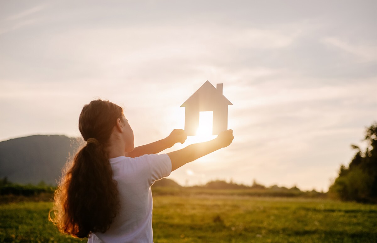 Mujer sujetando con sus manos la silueta de una casa