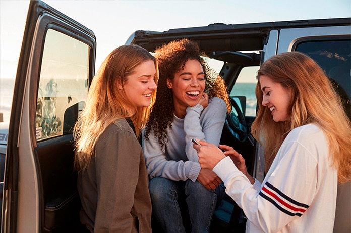 Grupo de amigas conversando junto a una furgoneta abierta durante una pausa en su viaje