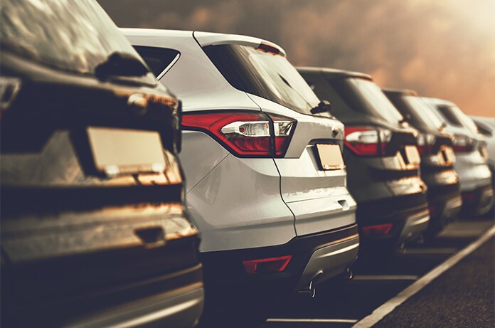 Fila de coches estacionados en batería, iluminados por una luz cálida al final del día