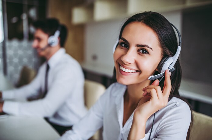 Dos personas con auriculares trabajando en una oficina, cada una utilizando un ordenador