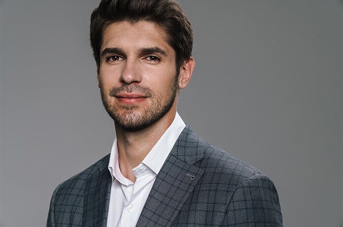 Retrato de una persona vestida con chaqueta y camisa sobre un fondo neutro de estudio