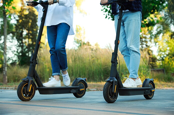 Dos personas conduciendo patinetes eléctricos en un entorno al aire libre