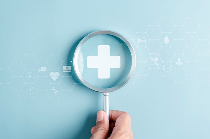 Lupa destacando una cruz sanitaria blanca sobre un fondo azul, acompañada de iconos médicos minimalistas distribuidos alrededor
