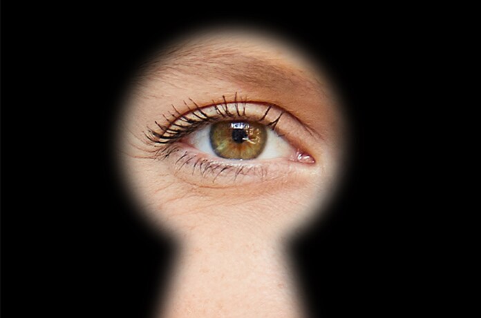 Ojo visto a través de la silueta de una cerradura sobre un fondo completamente oscuro