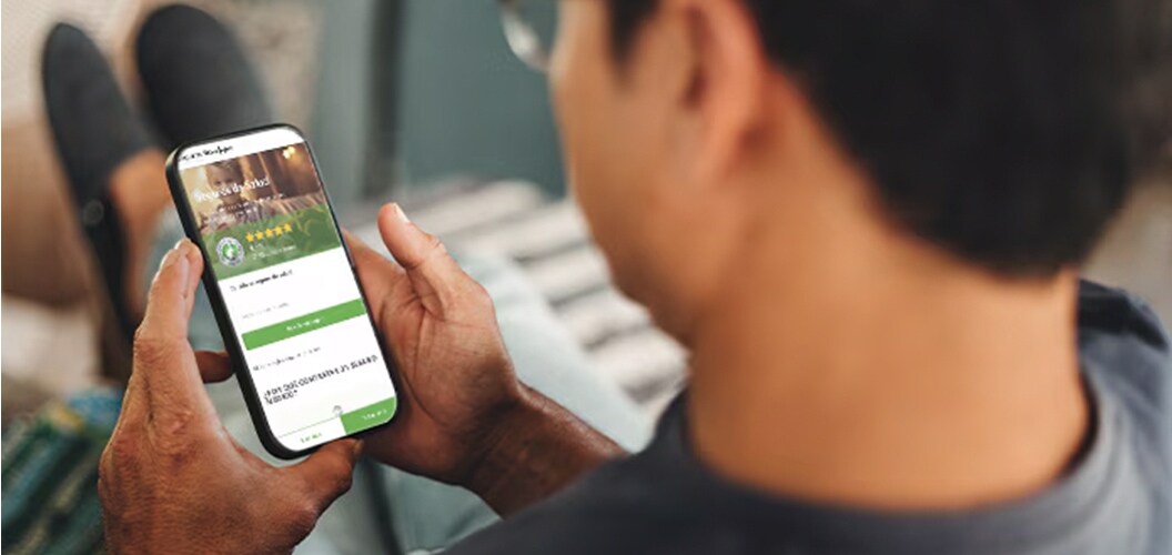 Persona consultando información en un teléfono móvil mientras permanece recostada en un sofá